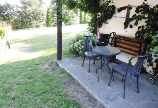 Patio at Bungalows Lubin Type A Jolanta in Germany with table, chairs, and greenery in a garden setting.