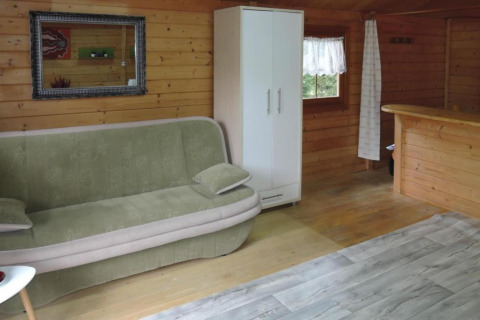 Intérieur de Bungalows, Lubin-Type B (Henryk) en Allemagne avec un canapé, armoire et murs boisés.