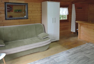 Interior of Bungalows, Lubin-Type B (Henryk) in Germany featuring a sofa, wardrobe, and wood walls.