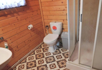 Badezimmer in einer Holzhütte mit Toilette, Dusche und gemustertem Boden, Bungalows Lubin-Type B, Deutschland.