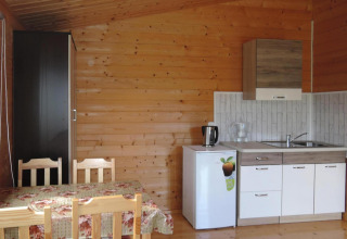 Cozy wooden cabin kitchen in Germany featuring a small table, chairs, mini fridge, sink, and cabinets.