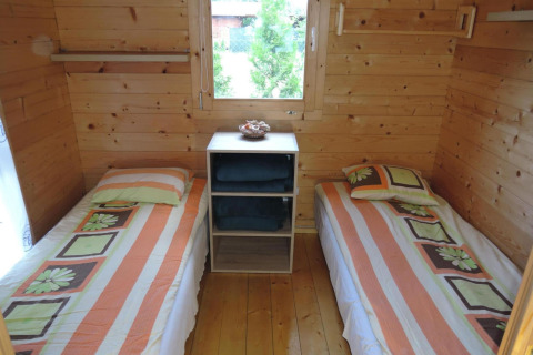 Cozy wooden cabin bedroom with two single beds and a window, at At «słonecznikiem» in Germany.