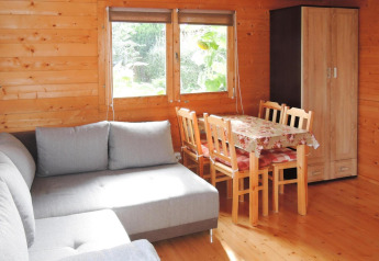 Interior de cabaña de madera en Alemania con sofá gris, mesa de comedor y armario junto a ventana.
