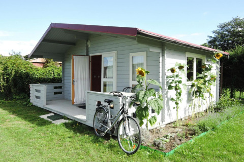 Acogedora cabaña de madera con bicicleta y girasoles fuera, tomada en At «słonecznikiem» en Alemania.