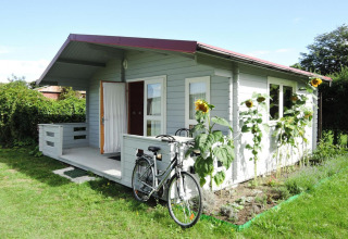 Cozy wooden cabin with a bicycle and sunflowers outside, taken at At «słonecznikiem» in Germany.