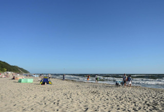 Personas disfrutan de un día soleado en una playa con olas y cielo azul cerca de At «słonecznikiem» en Alemania.