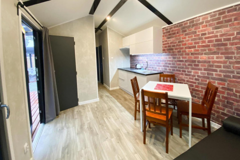 Moderne bungalow met keuken, eettafel voor vier en bakstenen muurdecor in Dziwnow, Duitsland.