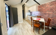 Interno di bungalow moderno con cucina, tavolo per quattro persone e parete in mattoni a Dziwnow, Germania.