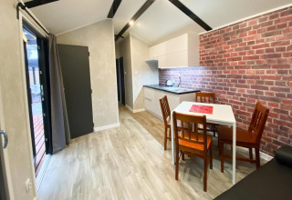 Moderne bungalow met keuken, eettafel voor vier en bakstenen muurdecor in Dziwnow, Duitsland.