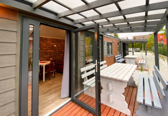 Terrasse des Bungalows Pirates à Dziwnow pour 4 personnes avec tables et bancs blancs en bois.