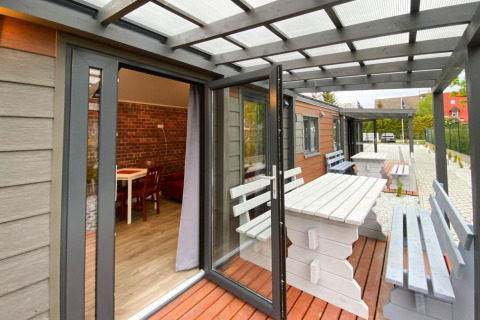 Terras van Bungalows Pirates in Dziwnow voor 4 personen met witte houten tafels en banken.