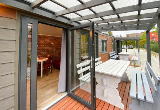 Terras van Bungalows Pirates in Dziwnow voor 4 personen met witte houten tafels en banken.
