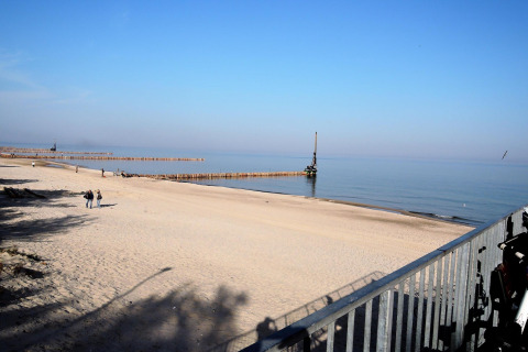 Vista desde la cabaña At «słonecznikiem» en Alemania con playa de arena, mar tranquilo y cielo azul despejado.