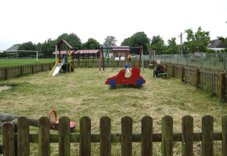 Parque infantil con columpios, tobogán y juegos, cercado, frente a la cabaña At «słonecznikiem» en Alemania.