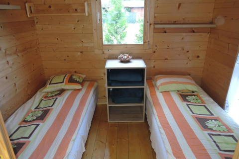 Twee enkele bedden met gestreept beddengoed in een gezellige houten hut in Duitsland, raamzicht.