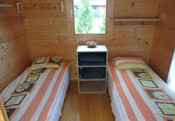 Dos camas individuales con ropa de cama a rayas en una acogedora cabaña de madera en Alemania.