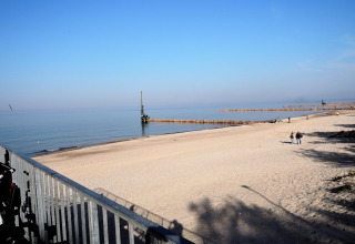 Vista de la playa desde la cabaña At «słonecznikiem» en Alemania, con arena, mar y personas paseando.