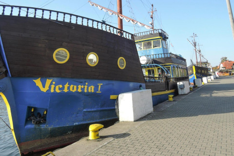 Foto van een piratenschip-thema woonboot Victoria I, aangemeerd aan de rivier in Dziwnow, Polen.