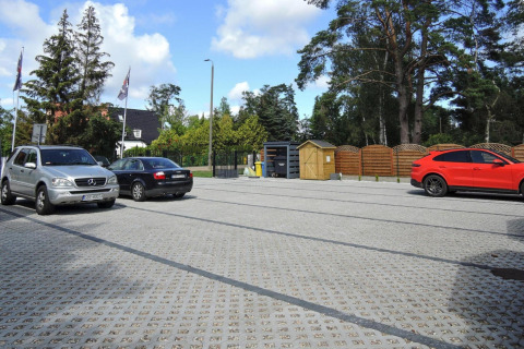 Parkeerterrein bij Bungalows Pirates in Dziwnow voor 4 personen, met geparkeerde auto's en bomen.