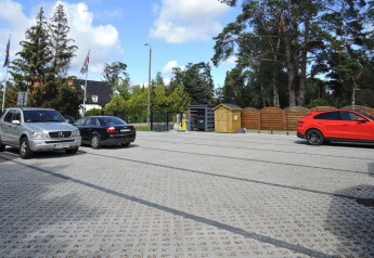 Parkplatz bei Bungalows Pirates in Dziwnow, Deutschland, mit mehreren Autos und grünem Hintergrund.