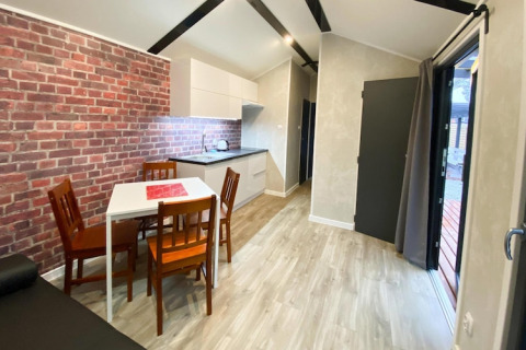 Moderne lodge met bakstenen muur, eethoek en open keuken bij Bungalows Pirates in Dziwnow, Duitsland.