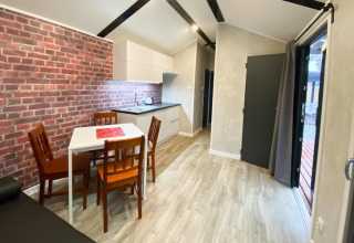 Moderne lodge met bakstenen muur, eetruimte en keuken bij Bungalows Pirates in Dziwnow, Duitsland.