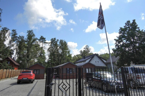 Ingang van Bungalows Pirates in Dziwnow, geparkeerde auto's en een wapperende piratenvlag op de binnenplaats.