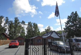 Ingang van Bungalows Pirates in Dziwnow met geparkeerde auto's en een piratenvlag in de voortuin.