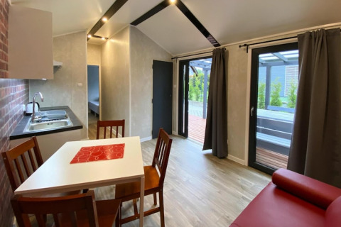Indvendigt billede af moderne bungalow med køkken, spisebord og adgang til udendørs terrasse.