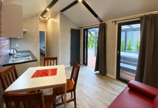 Binnenzicht van moderne bungalow met keuken, eettafel en toegang tot het terras te Dziwnow.