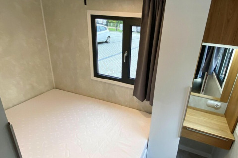 Slaapkamer met bed en raam bij Bungalows Pirates in Dziwnow voor 6 personen, modern ingericht.