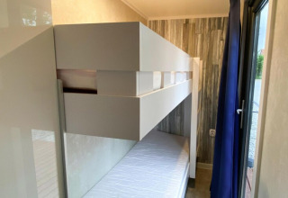 Moderne stapelbedden in een compacte kamer met houten muren in Bungalows Pirates in Dziwnow.