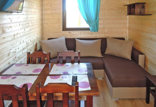 Living area at Holiday resort with the pool Wiselka Type A in Germany, with wood walls, sofa and dining table.