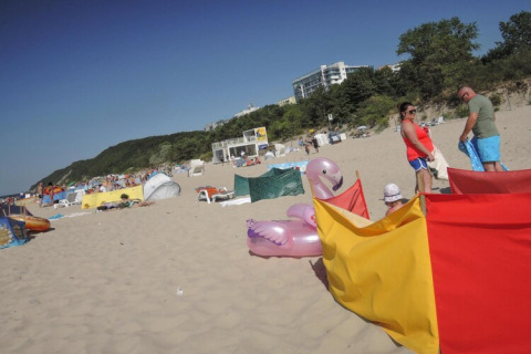 Strandtafereel bij Bungalows Pirates in Dziwnow met mensen, windschermen en opblaasbare speelgoed.