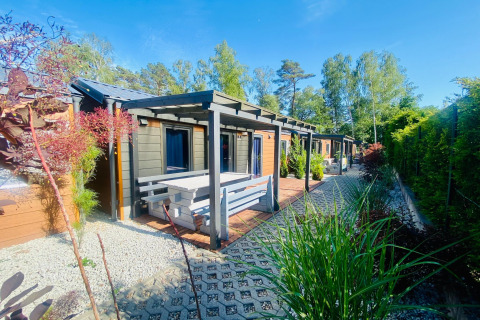Udendørs udsigt over Bungalows Pirates i Dziwnow med terrasse og bænk, omgivet af grønne planter.