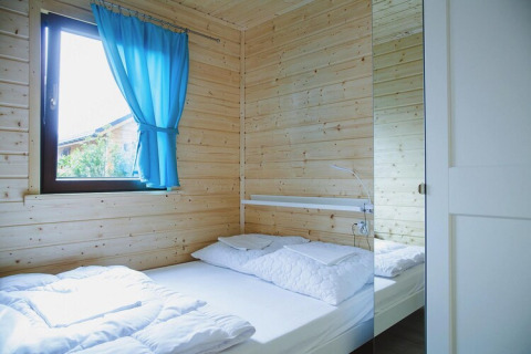 Camera luminosa con pareti in legno, tenda blu, letto matrimoniale e armadio a specchio in Germania.