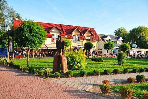 Holiday resort with pool Wiselka, 35 sqm Type A, surrounded by neat gardens and red-roofed buildings.