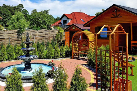 Resort vacanze a Wiselka, Germania, chalet in legno, fontana elegante e curato giardino ornamentale.