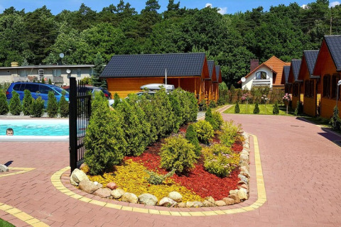 Outdoor area at Holiday resort with pool, surrounded by cabins, trees, and flower beds in Wiselka, Germany.