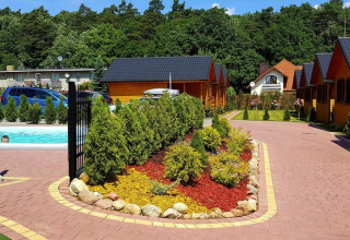 Outdoor area at Holiday resort with pool, surrounded by cabins, trees, and flower beds in Wiselka, Germany.