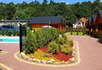 Buitenruimte van Holiday resort met zwembad, omringd door chalets, bomen en bloemenperk in Wiselka, Duitsland.