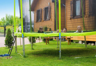 Children playing on a trampoline outside a wooden lodge at Holiday resort with the pool Wiselka-35 sqm Type A in Germany.