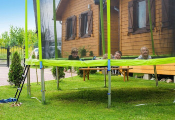 Kinderen spelen op een trampoline voor een houten lodge bij Holiday resort with the pool Wiselka-35 sqm Type A in Duitsland.