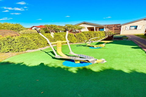 Attrezzature fitness all'aperto su prato verde al Holiday Resort Wiselka, circondate da siepi e bungalow in Germania.
