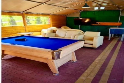 Rekreationsområde med billardbord, sofaer, tv og bordfodbold på Holiday Resort Wiselka i Tyskland.