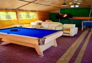 Recreatieruimte met pooltafel, zetels, tv en tafelvoetbal in het Holiday Resort Wiselka in Duitsland.