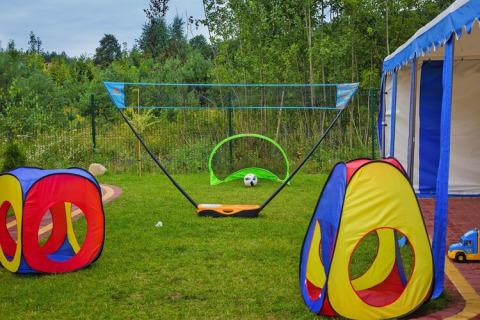 Outdoor play area at Holiday resort with colorful tents, a ball, toy truck, and green scenic background.