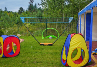 Outdoor play area at Holiday resort with colorful tents, a ball, toy truck, and green scenic background.
