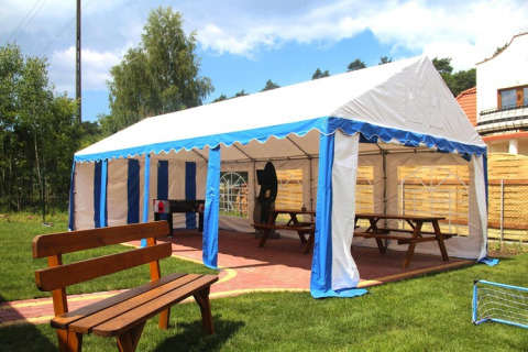 Outdoor marquee with blue and white stripes, benches and picnic tables at Wiselka holiday resort, Germany.