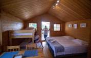 Cabaña de madera con cama doble, literas y comedor en Holiday homes in Miedzyzdroje, Alemania.